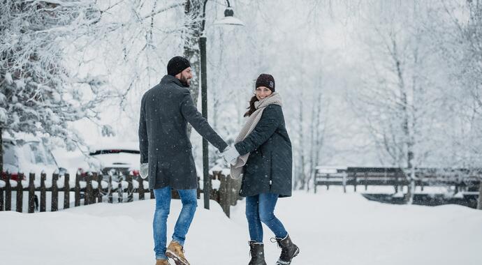 Paar Hand in Hand im verschneiten Park, Winterkleidung