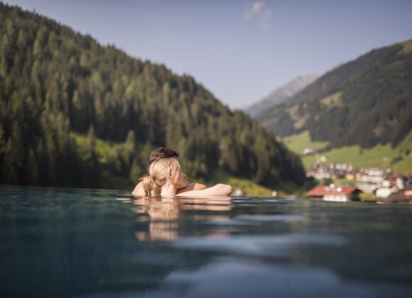 Frau im Pool mit Blick auf grüne Berge