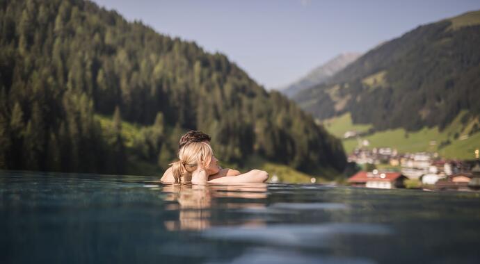 Frau im Pool mit Blick auf grüne Berge