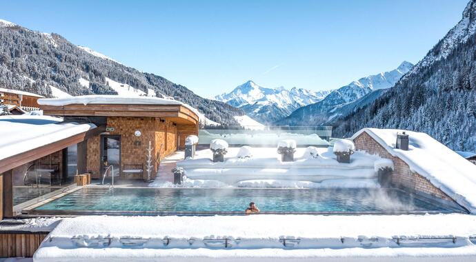 Hotel Tuxerhof in winter with snow, rooftop pool and mountains in the background