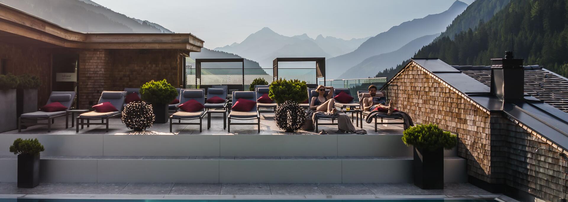 Pool area with loungers in front of a mountain panorama