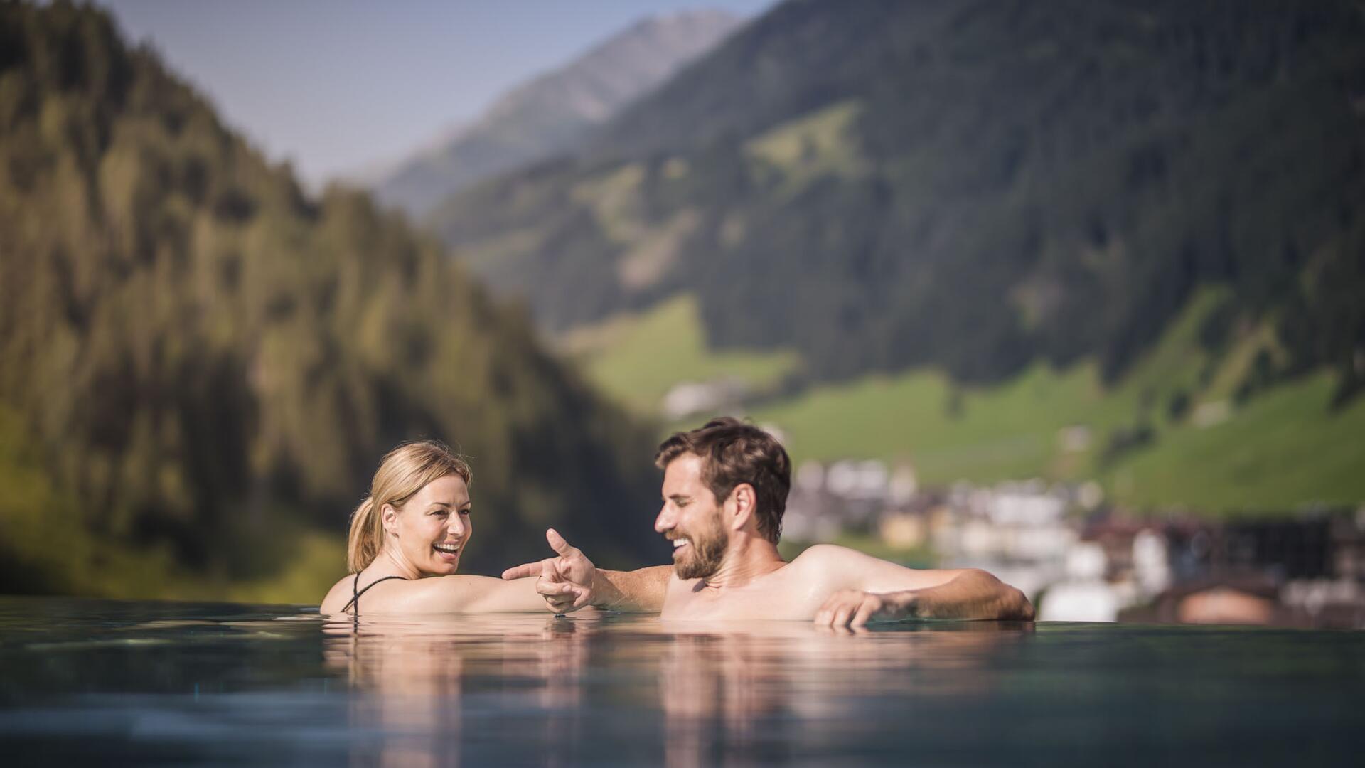 Frau und Mann im Pool vor Berglandschaft