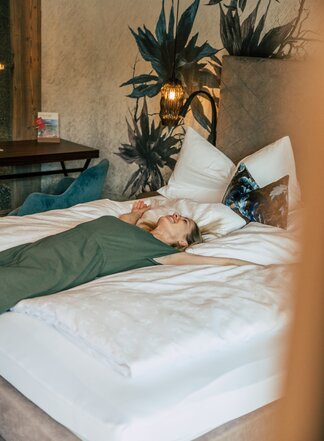 Woman relaxing on the bed in a cozy Tuxerhof room
