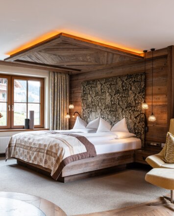 Geräumiges Hotelzimmer mit Doppelbett, Holzelementen und gemütlicher Sitzecke