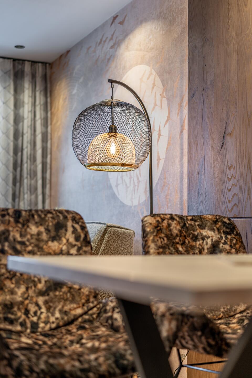 Floor lamp with spherical lampshade above table and armchairs