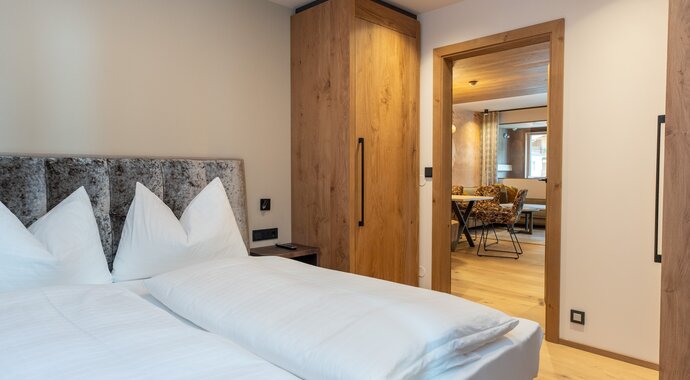 Children&#39;s room with double bed, wooden wardrobe and passage to a living area