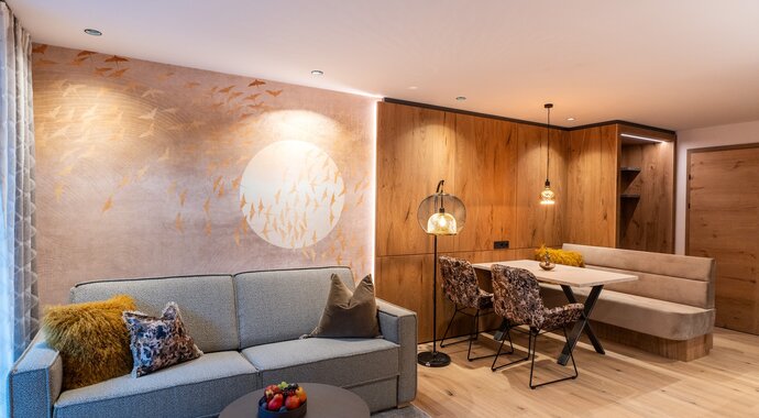 Living room of a junior suite with sofa, table, chairs and wooden wall