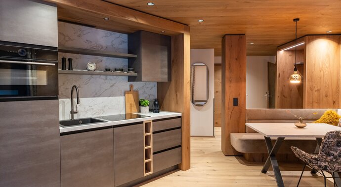 Modern kitchen with grey cabinets, wooden beams and light wooden floor in Suite BergZEIT