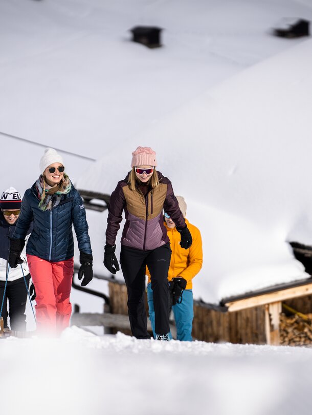 Group snowshoeing in the snow in front of a hut
