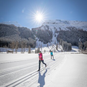 Langläuferinnen gleiten bei Sonnenschein durch die verschneite Landschaft von Tux